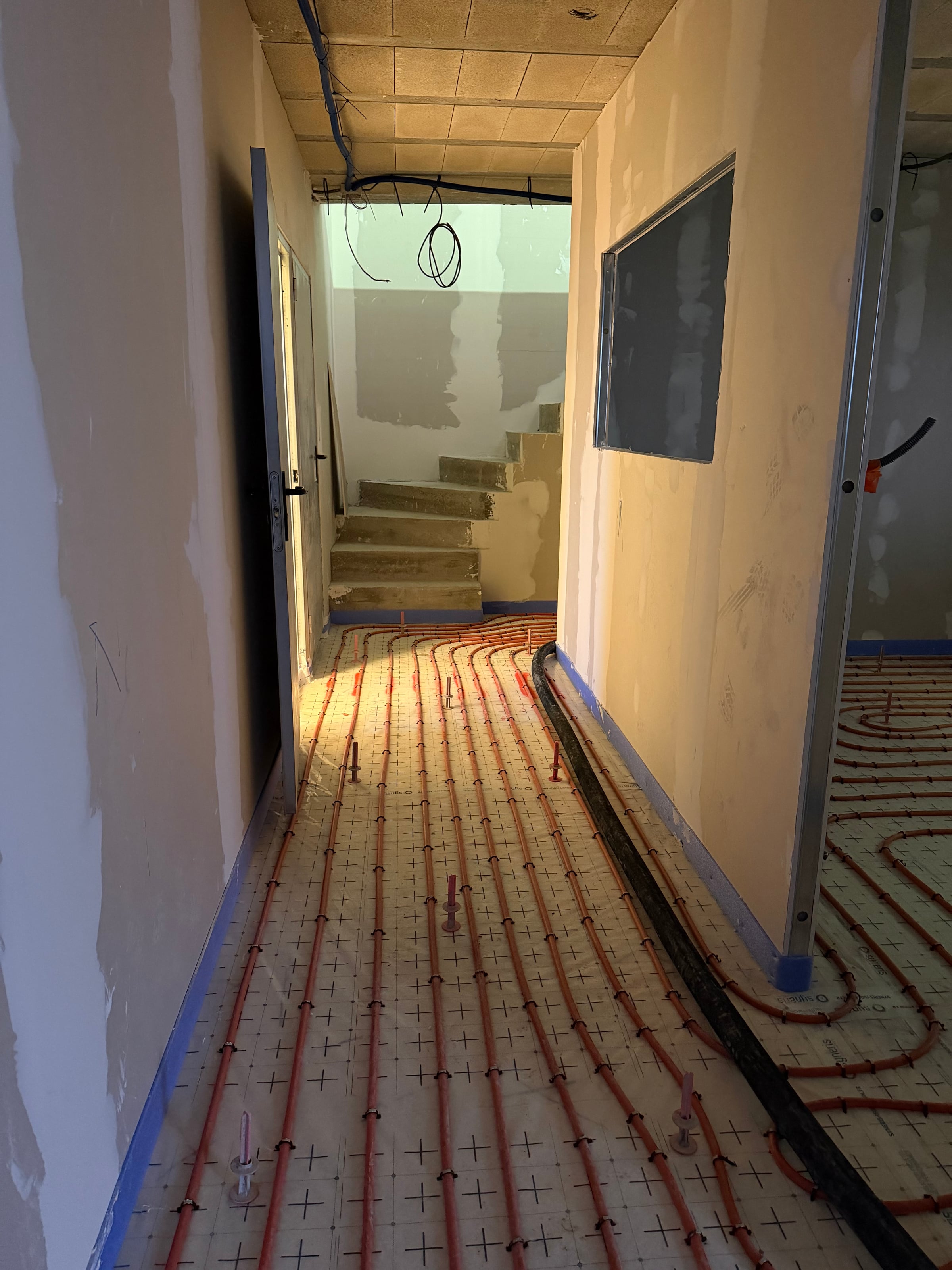 Couloir avec tubes PER de plancher chauffant posés avant coulage chape fluide · Isolatech