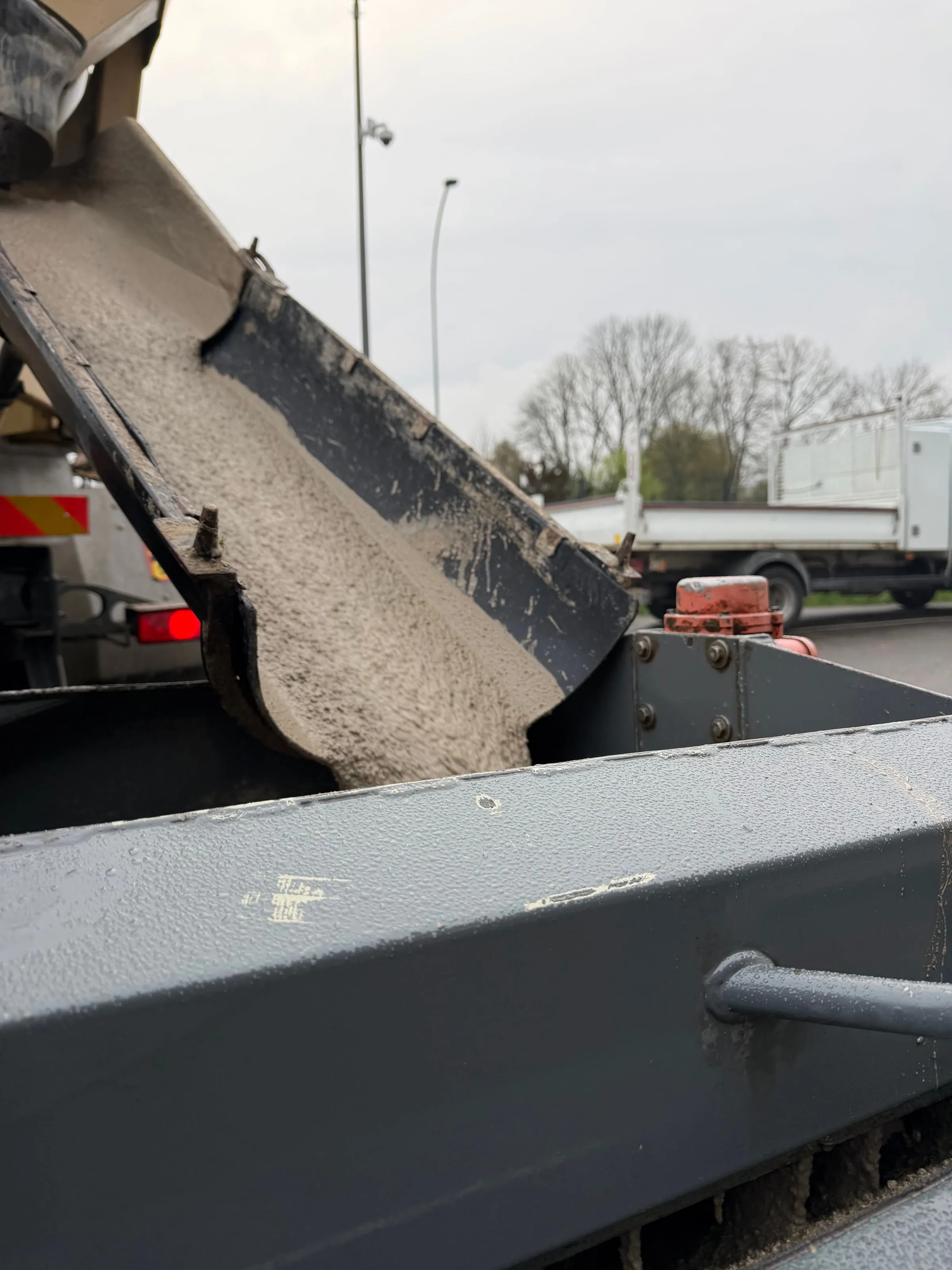 Goulotte de camion-toupie versant chape fluide sur chantier · Isolatech
