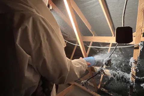 Applicateur Isolatech en plein soufflage de ouate de cellulose dans les combles, charpente bois apparente · Saint-Barthélemy (70200, près de Lure, Haute-Saône) · Isolatech