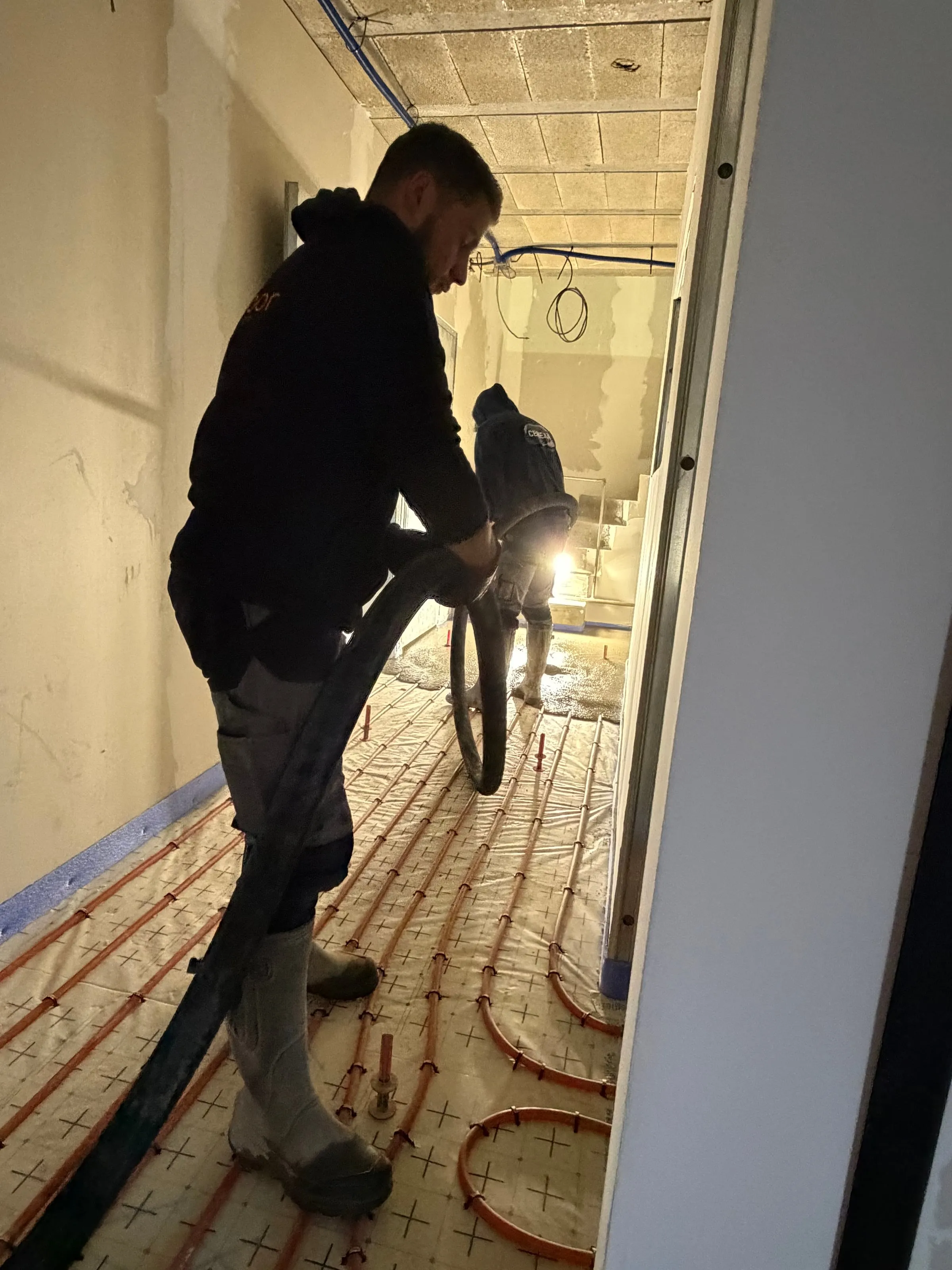 Chapiste Isolatech tirant un tuyau PER sur chantier de chape fluide