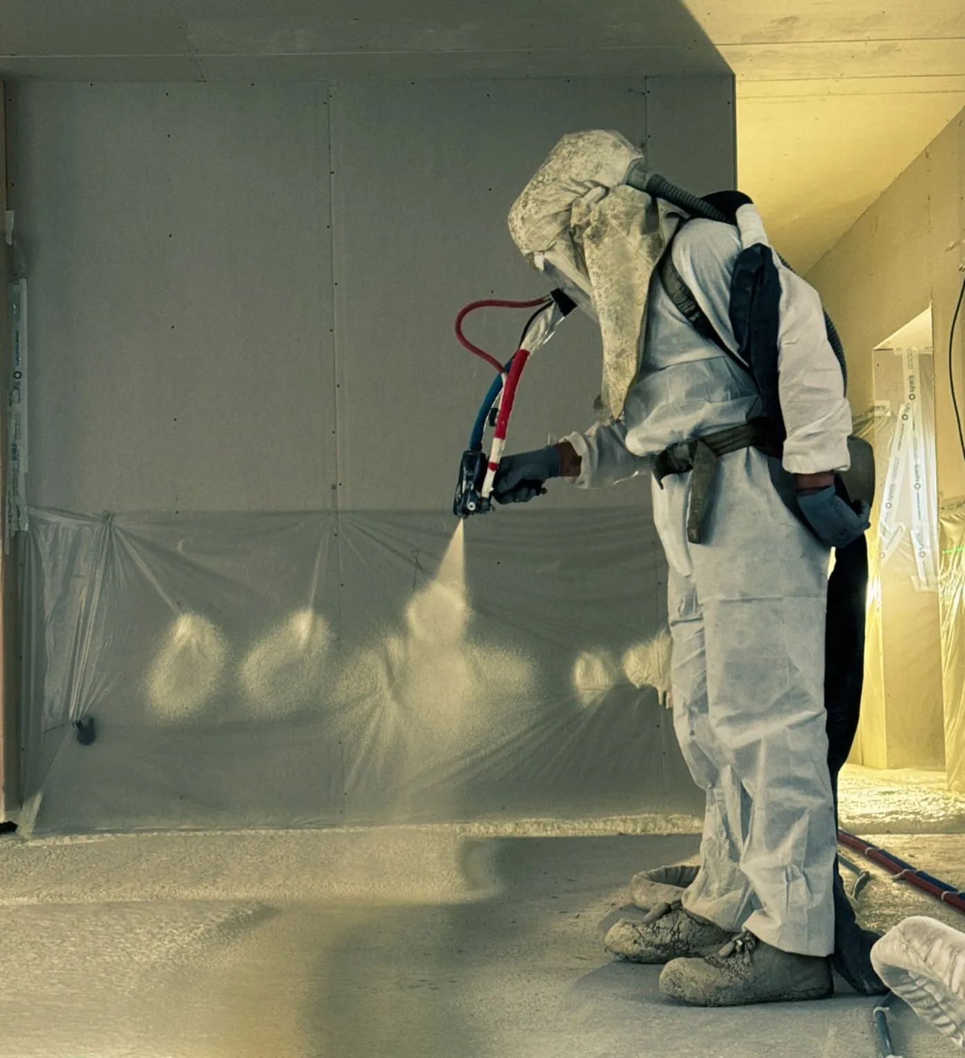 Applicateur Isolatech projetant la mousse polyuréthane sur mur intérieur, lumière dorée
