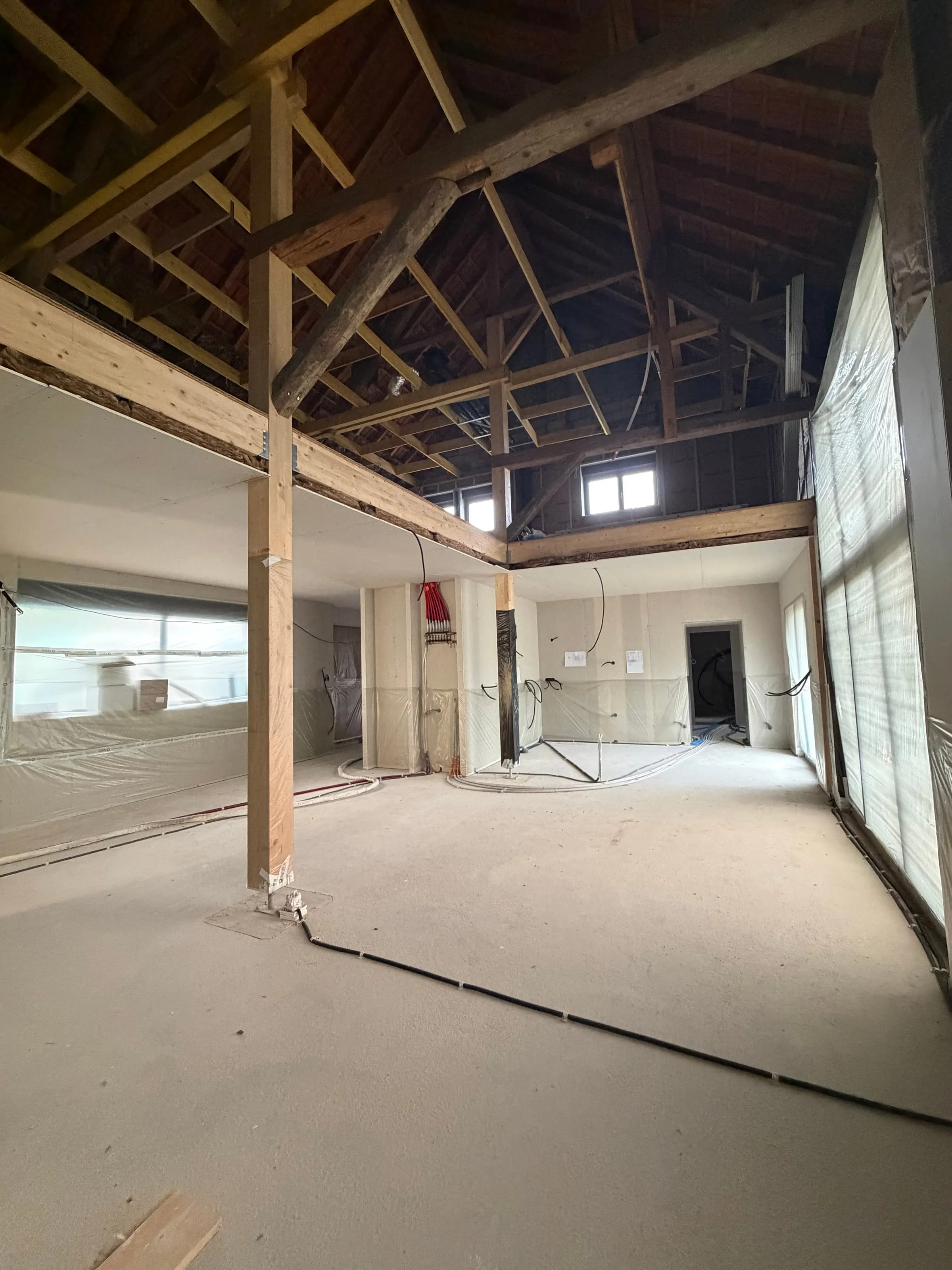 Vue d'ensemble de la grande pièce loft avec charpente bois apparente et toiture, avant projection polyuréthane des sols · Pérouse · Isolatech